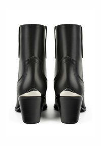Bottines en cuir noir avec un bout pointu et un large talon. Présentent un accent métallique à l'arrière et des détails de couture subtils.