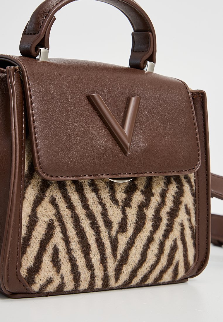 Braune Lederhandtasche mit einer Vorderklappe aus Filz im Zebra-Muster, ausgestattet mit einem Frontverschluss und einem oberen Tragegriff. Verstellbarer Trageriemen enthalten.