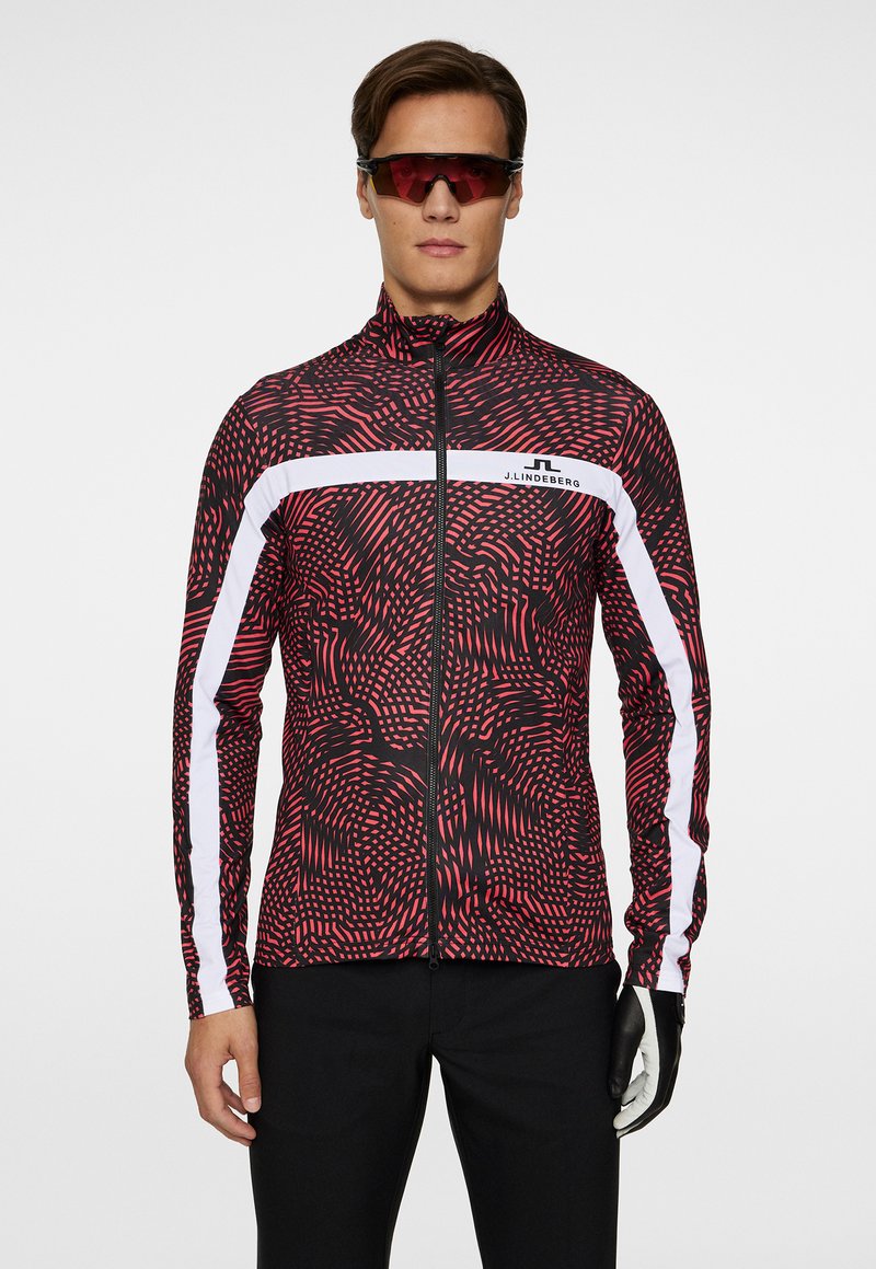 Röd och svart mönstrad träningsjacka med full dragkedja och vita accentlinjer. Slät textur, långa ärmar och figursydd design.