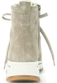 Botas de ante hasta el tobillo en beige claro con una suela de goma blanca texturizada. Las características incluyen un cierre con cremallera y un lazo ajustable en la parte posterior.