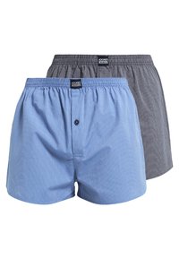Dos pares de calzoncillos para hombre: uno azul con rayas blancas verticales y otro gris con rayas finas. Ambos tienen cinturillas elásticas y detalles de botones.