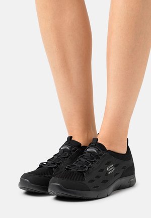 Svarta sportskor med övre meshmaterial, strukturerade detaljer och snörning. Lätt design med diskret logotyp och dämpade sulor.