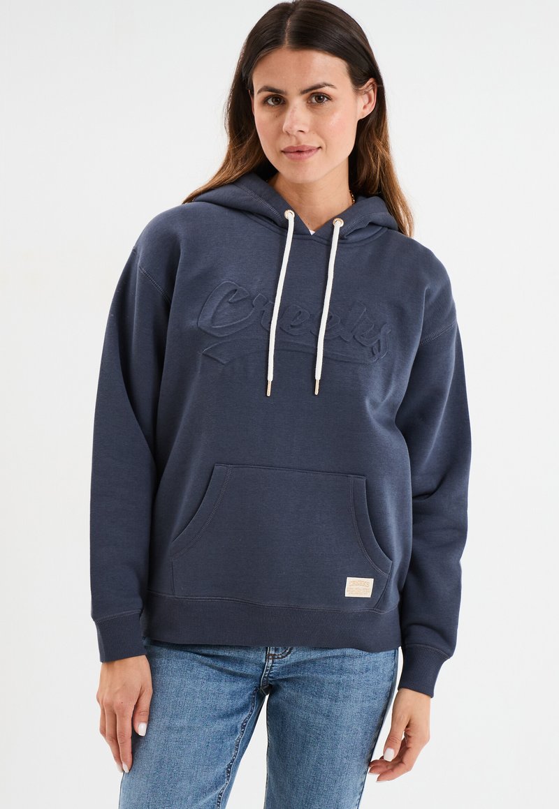 Sweat-shirt à capuche bleu marine avec un logo texturé, poche avant et cordons en crème. Tissu doux avec des poignets et un ourlet côtelés.