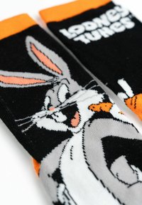 Calzini neri e arancioni con Bugs Bunny che tiene una carota e il testo "Looney Tunes" sulla parte superiore della fascia.