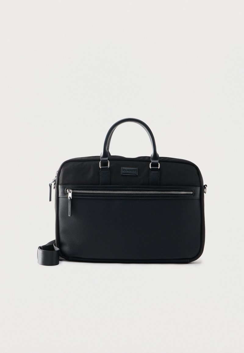 Μαύρη ορθογώνια τσάντα γραφείου με διπλές λαβές, μπροστινή τσέπη με φερμουάρ και αποσπώμενο ιμάντα ώμου σε απλό λευκό φόντο.