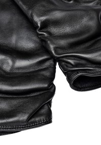 Mustat nahkahansikkaat, joissa on sileä pinta, poimuttunut muotoilu, hieman ryppyinen ulkonäkö ja pehmeä sisävuori lisämukavuutta varten.