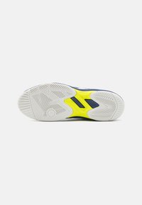 Sole sneakeru z gumy s texturovaným bílým vzorem a jasně žlutým akcentem. Obsahuje tmavě modrou mezipodešev a aerodynamický design.