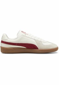 Hvit sneaker med rød semsket stripe, teksturert gummisåle og glatt skinnoverdel. Har snøring og logo på tungen.