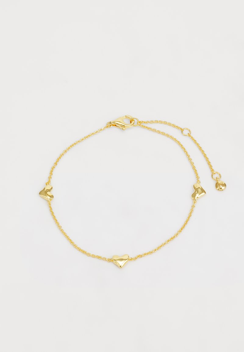 Kuldne käevõru, millel on kolm südamekujulist aksessuaari, karabiinklips ja reguleeritav kett suuruse kohandamiseks.