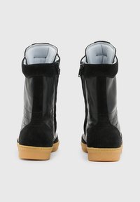 Stivaletti alla caviglia in pelle e suede nera con finitura texture, chiusura a zip e suola in gomma color cammello. Fodera morbida e dettagli con colletto imbottito.