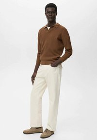 Suéter marrón de punto acanalado, pantalones de corte relajado en crema claro y zapatos color tan con cordones. Diseño sencillo con cuello tipo camisa y textura sutil.