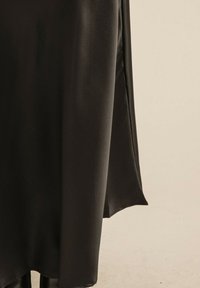 Robe en satin noir avec un design fluide et une légère brillance, des manches longues et une silhouette subtilement drapée.