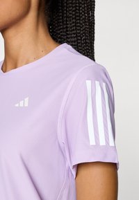 Lichtpaarse prestatie T-shirt van een textuurstof, met witte drie-streepaccenten op de linkerschouder en een ronde hals.