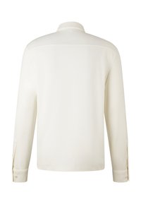 Langarmshirt van ivoorkleurige stof. Beschikt over een kraag, knoopmanchetten en een soepele textuur met een rechte achterkant.