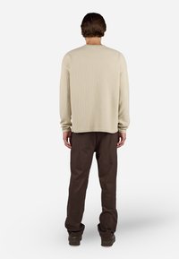 Langærmet, lys beige sweater med tekstureret m�ønster, parret med løstsiddende, mørkebrune bukser. Enkel design, afslappet pasform.
