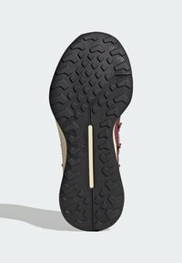 Semelle extérieure en caoutchouc noir avec des profondeurs prononcées, présentant un design texturé et une semelle intermédiaire beige. Comprend un accent en barre au centre.