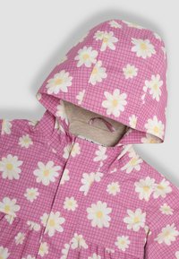 Růžový pláštěnka s mřížkovaným vzorem a bílým potiskem sedmikrásky. Má kapuci, zapínání na knoflíky a hladkou texturu.