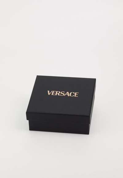Caja de regalo rectangular negra con un acabado texturizado y un logo en relieve dorado "VERSACE" en la parte superior. Sin herrajes ni adornos visibles.