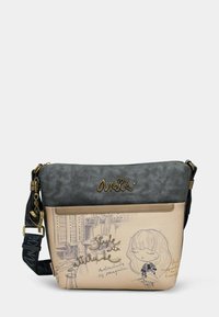 Borsa a tracolla con parte superiore in ecopelle scura. La sezione inferiore beige presenta un disegno di una ragazza e del testo. Tracolla nera con dettagli metallici.