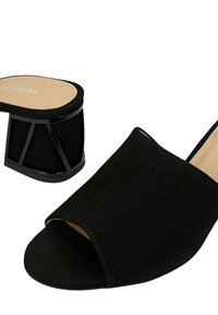 Mules ouverts en daim noir avec un talon en bloc noir géométrique distinctif et une semelle intérieure lisse couleur tan. Présente une texture douce et des coutures minimales.