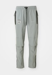 Gray athletic pants with a drawstring waist, side zipper pockets, and knee accent panels. Features a logo on the front left thigh and brand emblem.