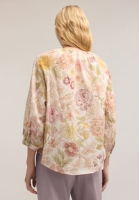 Blommig blus i lätt tyg, med pastellfärger i rosa, gula och gröna blommor. Lätt lös passform med 3/4 ärmar och rynkad halsringning.