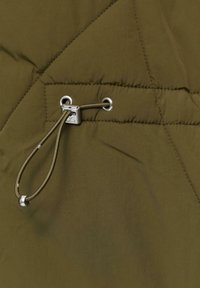 Olijfgroene gewatteerde stof met een gladde textuur, voorzien van een zilveren metalen oogje en een trekkoorddetail voor aanpassing.