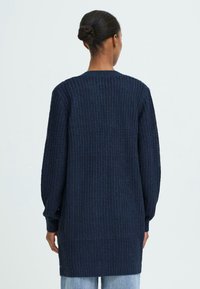 Marineblå strikket cardigan med et tekstureret mønster, lange ærmer og en afslappet pasform, med ribbede manchetter og kant, der går til midten af låret.