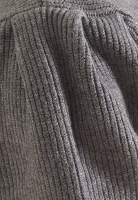Grau gestrickter Stoff mit geripptem Muster, weichen, flauschigen Fasern und sanftem Fall. Das Material wirkt dick und warm.