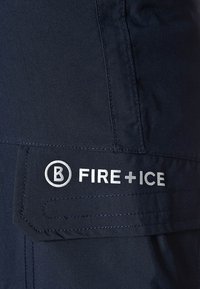 Mörkblå byxor i slitstarkt material med en sidficka som har en silverfärgad "B FIRE+ICE" logo och rena sömdetaljer.