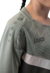 Groene sportshirt met een textuurpatroon, grijze accenten en een logo, met een ronde hals en een gedetailleerd schouderontwerp.