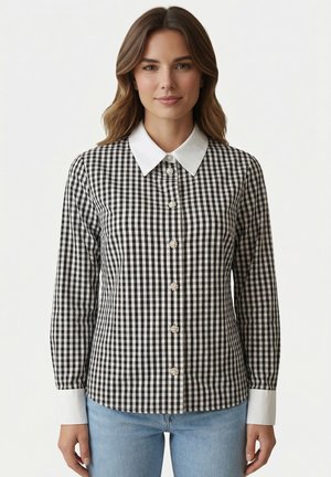 Donna con capelli castano chiaro che indossa una camicia a quadri bianca e nera a maniche lunghe con colletto e polsini bianchi, abbinata a jeans azzurri.