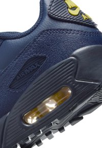 Tumes sinise nahast tennis, millel on nähtav õhuelement, tekstuuriga aktsendid ja must kummist talla muster. Sisaldab "Air Max" brändingut.