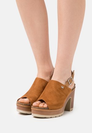 Brown suede platform sandals with an open toe and slingback design. Features a chunky heel and light-colored rubber sole. Silver buckle detail.