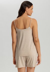Conjunto de loungewear beige con parte superior de tirantes finos y pantalones cortos a juego. Tejido suave y ligero con una textura sutil. Ajuste casual.