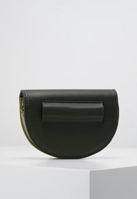 Czarna półokrągła skórzana torebka kopertowa z przeszywanym prostokątnym uchwytem z przodu, prezentowana na białym postumencie na jednolitym tle.