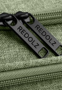 Groen, gestructureerde stof met zwarte ritsen die het merk "REDOLZ" weergeven. De ritsen hebben rechthoekige labels met gaten voor gemakkelijke grip.
