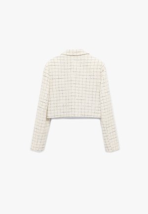 Veste raccourcie en tissu texturé blanc avec un motif à carreaux, dotée de manches longues et d'un col à revers.