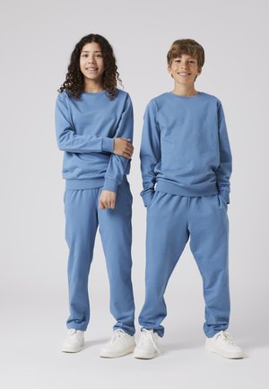 Light blue sweatshirt and sweatpants set made of soft cotton, featuring ribbed cuffs and waistband, complemented by white sneakers.