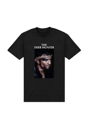 Sort T-shirt med et fremtrædende billede af en mand med pandebånd, beskidt ansigt og teksten "THE DEER HUNTER" ovenfor portrættet.