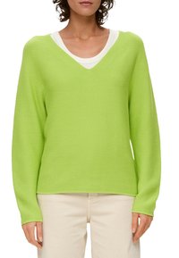 Limonkowy sweter w serek z długimi rękawami, o teksturowanym wzorze dzianiny i ściągaczach, nałożony na biały t-shirt.