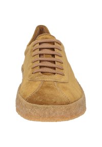 Baskets en daim jaunes avec un bout arrondi, semelle en caoutchouc et lacets marron. La tige présente des sections lisses et texturées.