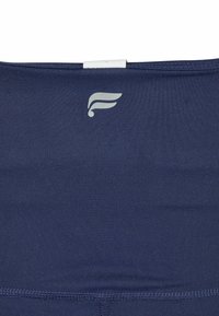 Navy fabric sports top with a smooth texture, featuring a small silver logo on the left side and a clean, streamlined design.