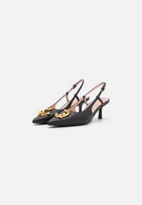 Tocuri cu toc slingback din piele neagră, cu vârf ascuțit, prezentând un accent din lanț auriu și o curea texturată. Toc subțire stilletto.