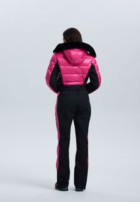 Mono de esquí acolchado en rosa y negro, con una chaqueta corta que tiene un cuello de piel sintética y pantalones con bloques de color y acentos laterales.