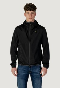 Giacca nera impermeabile con cappuccio, zip frontale, polsini ed orlo elasticizzati, con un piccolo logo sul petto e tasche laterali.