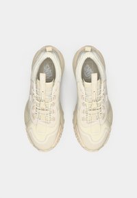 Jasno beżowe sneakersy z fakturowaną cholewką, systemem sznurowania, wyściełaną podeszwą oraz logo Vans po boku i na języku.