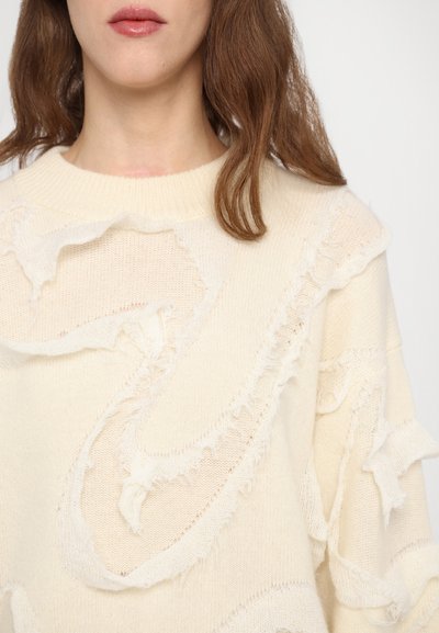 Ivory knit sweater with frayed, textured detailing and a ribbed crew neckline. Features a loose fit and soft, lightweight fabric.