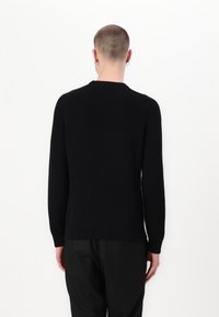 Pull noir côtelé avec un col rond, des manches longues et une coupe décontractée. Présente un motif tricoté texturé et des côtes aux poignets et à l'ourlet.