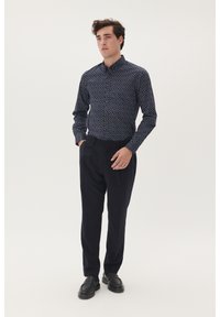 Marineblauwe overhemd met een wit patroon, gecombineerd met donkere nette broeken. Het shirt heeft een kraag en lange mouwen. Zwarte schoenen maken het geheel af.